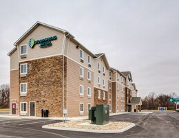 A multi-story hotel with a stone facade and a sign reading "Woodspring Suites".