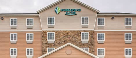 A multi-story hotel with a stone facade and a sign reading "Woodspring Suites".