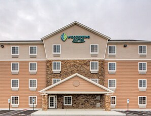 A multi-story hotel with a stone facade and a sign reading "Woodspring Suites". - WoodSpring Suites Columbus NE I-270 Airport (Columbus)