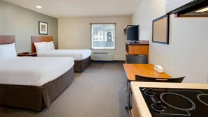 Une chambre d’hôtel avec deux lits, un bureau, une télévision et une kitchenette.
