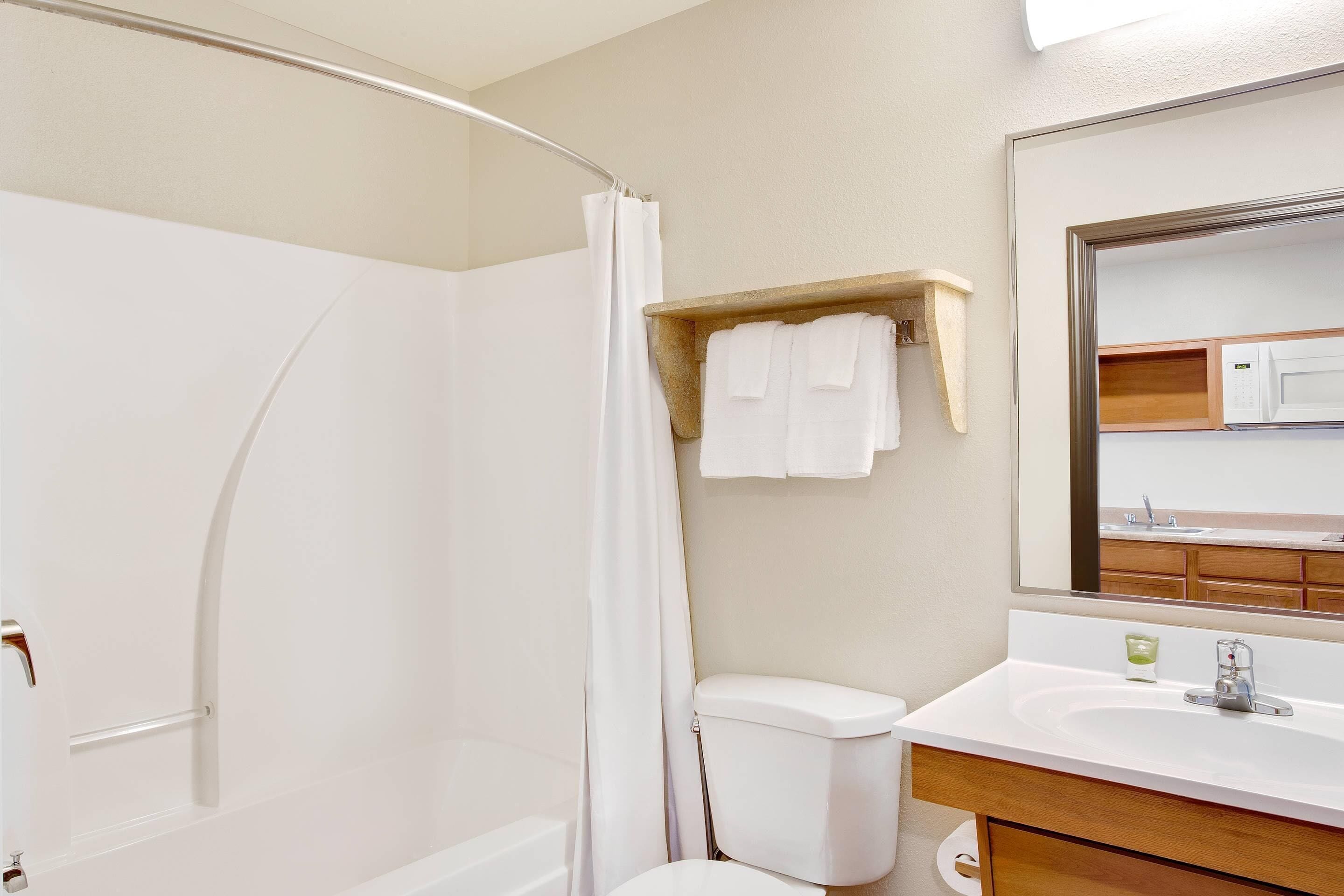 Un baño con ducha, inodoro, lavamanos y espejo.