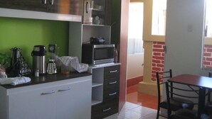 A compact kitchen with white cabinets, a microwave, and a coffee maker. - Mango Hostel Bed & Breakfast (Arequipa)