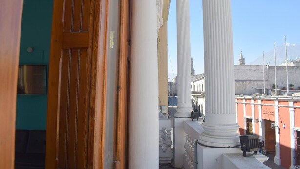 A view of a building's interior with wooden doors and white columns. - Mango Hostel Bed & Breakfast (Arequipa)