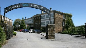 Entrada de un edificio con un cartel que dice 'Pousada de Portomarin' y un camino de entrada con portones.