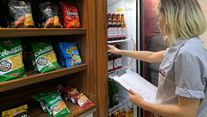 Una persona sacando cosas de un refrigerador lleno de aperitivos y bebidas.