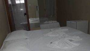 A hotel room with a bed, a small table, and a mirror. - Pousada Estrela do Vale (Taubate)