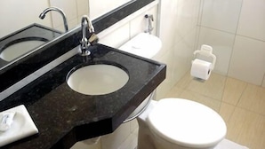 A bathroom with a black marble sink, a white toilet, and a white toilet paper holder. - Pousada Estrela do Vale (Taubate)