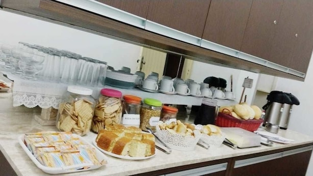 A buffet setup with various food items and utensils. - Pousada Estrela do Vale (Taubate)