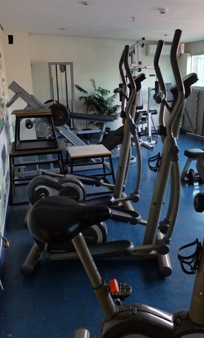 A gym with exercise equipment including treadmills, elliptical machines, and a weight bench. - Olavo Bilac Hotel (Taubate)