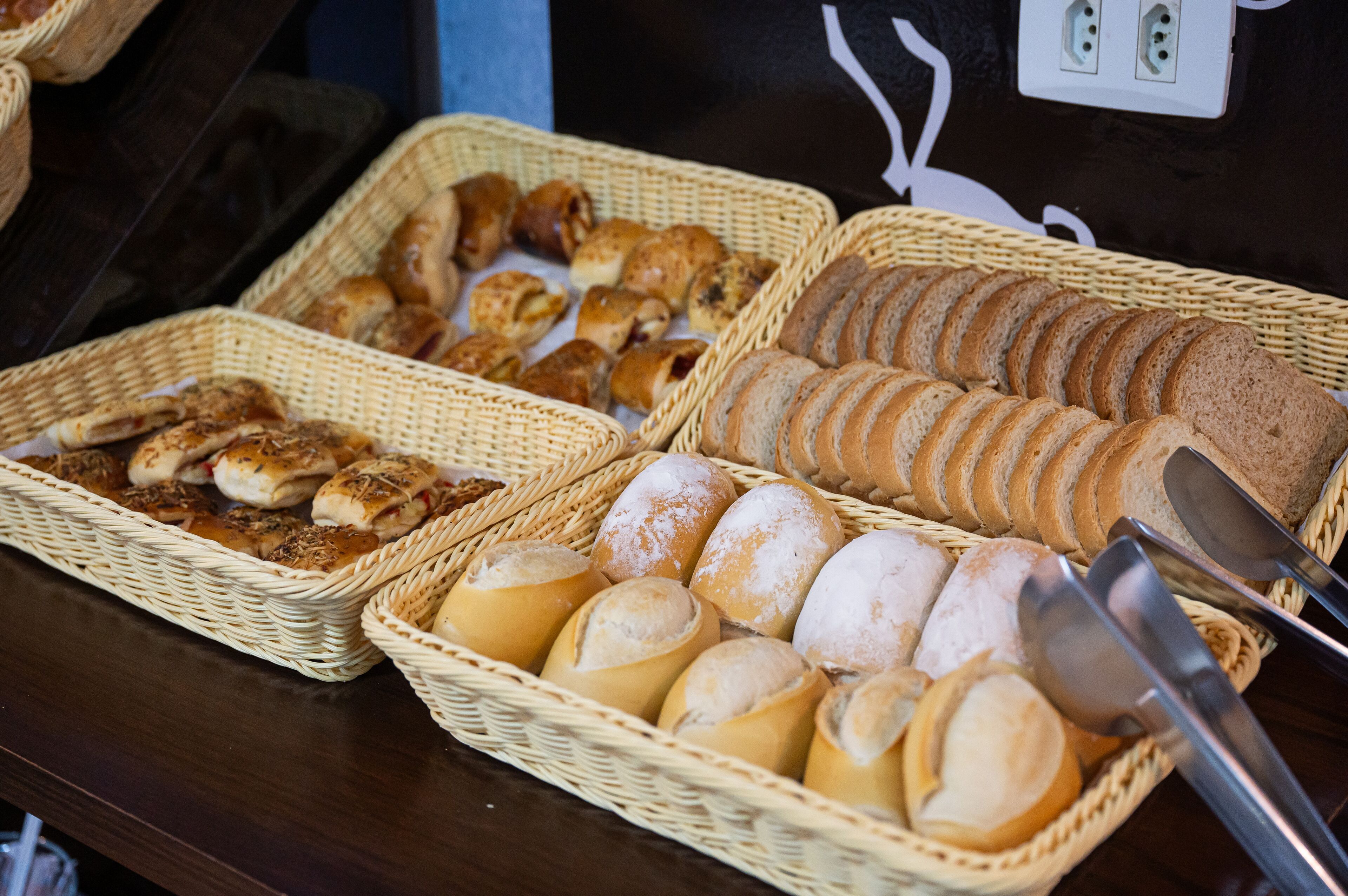 A buffet table with various breads and pastries in wicker baskets.