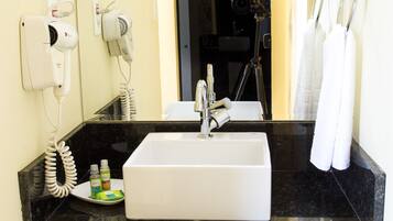 Un baño con lavabo, espejo, secador de pelo y toallero.