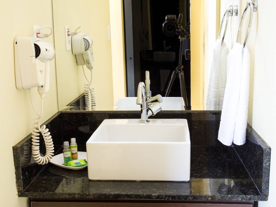 Un baño con lavabo, espejo, secador de pelo y toallero.