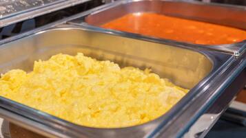A buffet with scrambled eggs and a red sauce.