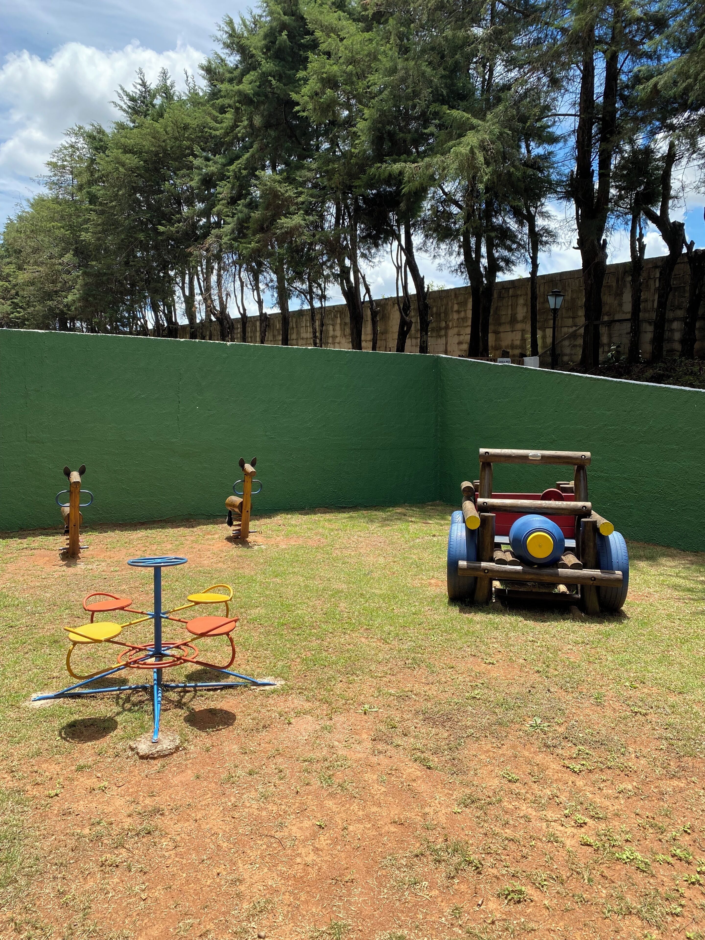 Un patio de juegos con un coche neumático, columpios y una estructura para escalar.