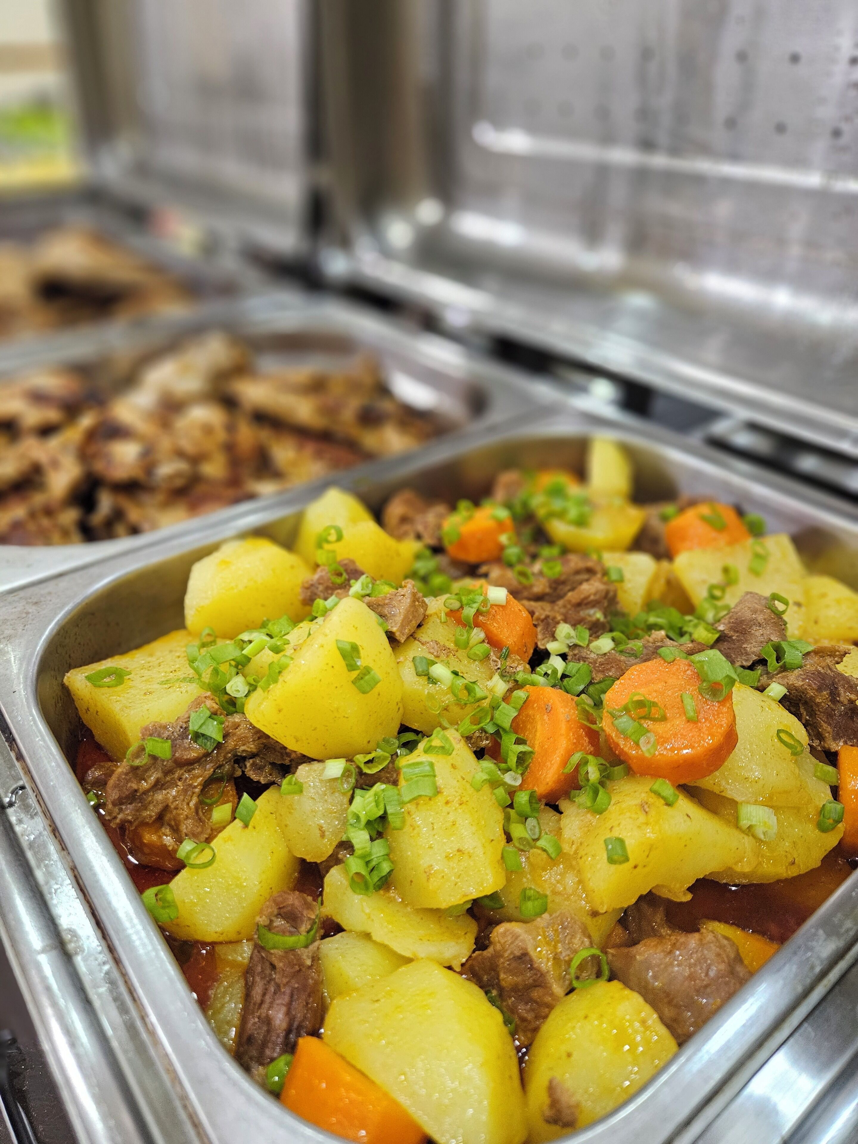 Un bufé con una variedad de platos, incluyendo un guiso de carne y patatas adornado con cebollines.