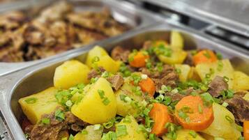 Un bufé con una variedad de platos, incluyendo un guiso de carne y patatas adornado con cebollines.