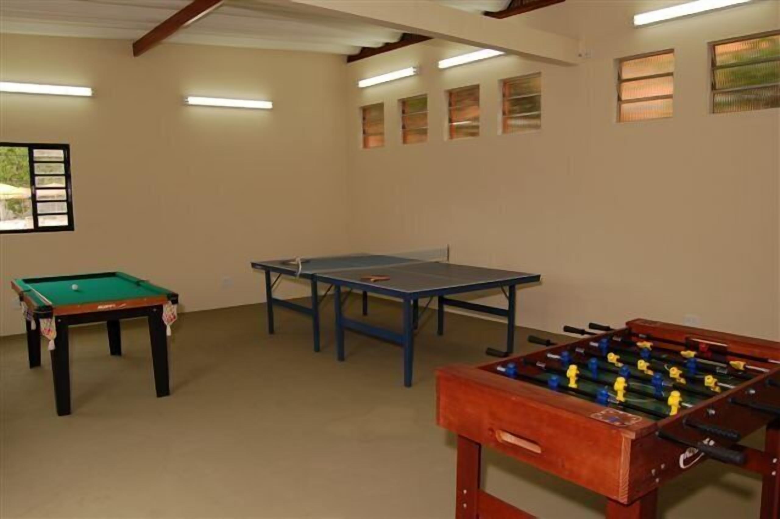 A room with a pool table, foosball table, and ping pong table.