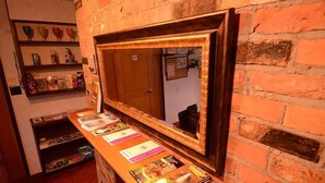 A reception area with a wooden counter displaying brochures, a mirror, and a brick wall. - Fairy's Garden Chalet (West Kelowna)