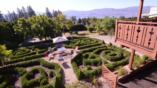 A garden with a maze, outdoor seating, and a view of mountains. - Fairy's Garden Chalet (West Kelowna)