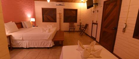 A hotel room with two beds, a small seating area, and a television mounted on the wall.