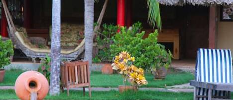 A pool area with a water feature, a hammock, a chair, and potted plants.