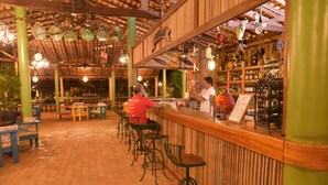 Un área de bar con mobiliario de madera y adornos colgantes.