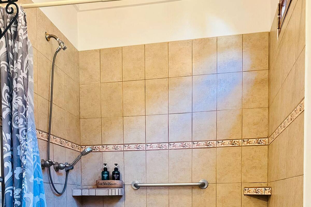 A bathroom with a toilet, shower, and a wooden bench.