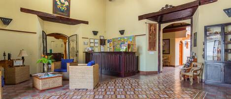 A spacious lobby with a checkered floor, wicker furniture, and a reception desk.