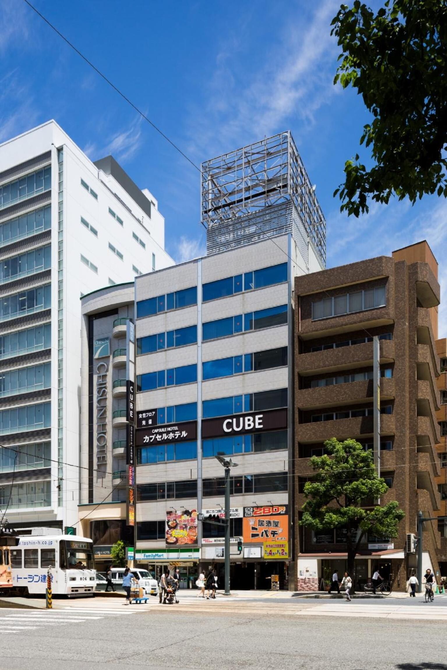 A modern building with a prominent 'CUBE' sign, surrounded by other commercial buildings and a tram.