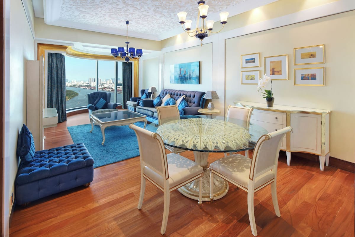 A spacious living room with a large glass table, comfortable seating, and a view of the city.