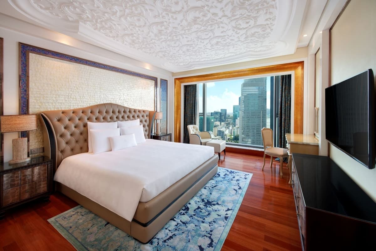 A spacious hotel room with a large bed, a television, and a view of the city skyline.