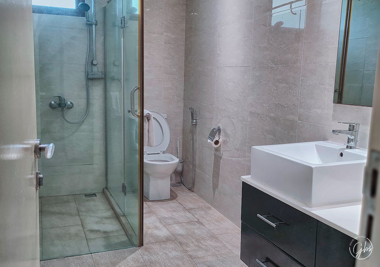 A bathroom with a glass-enclosed shower, a toilet, and a sink with a mirror.