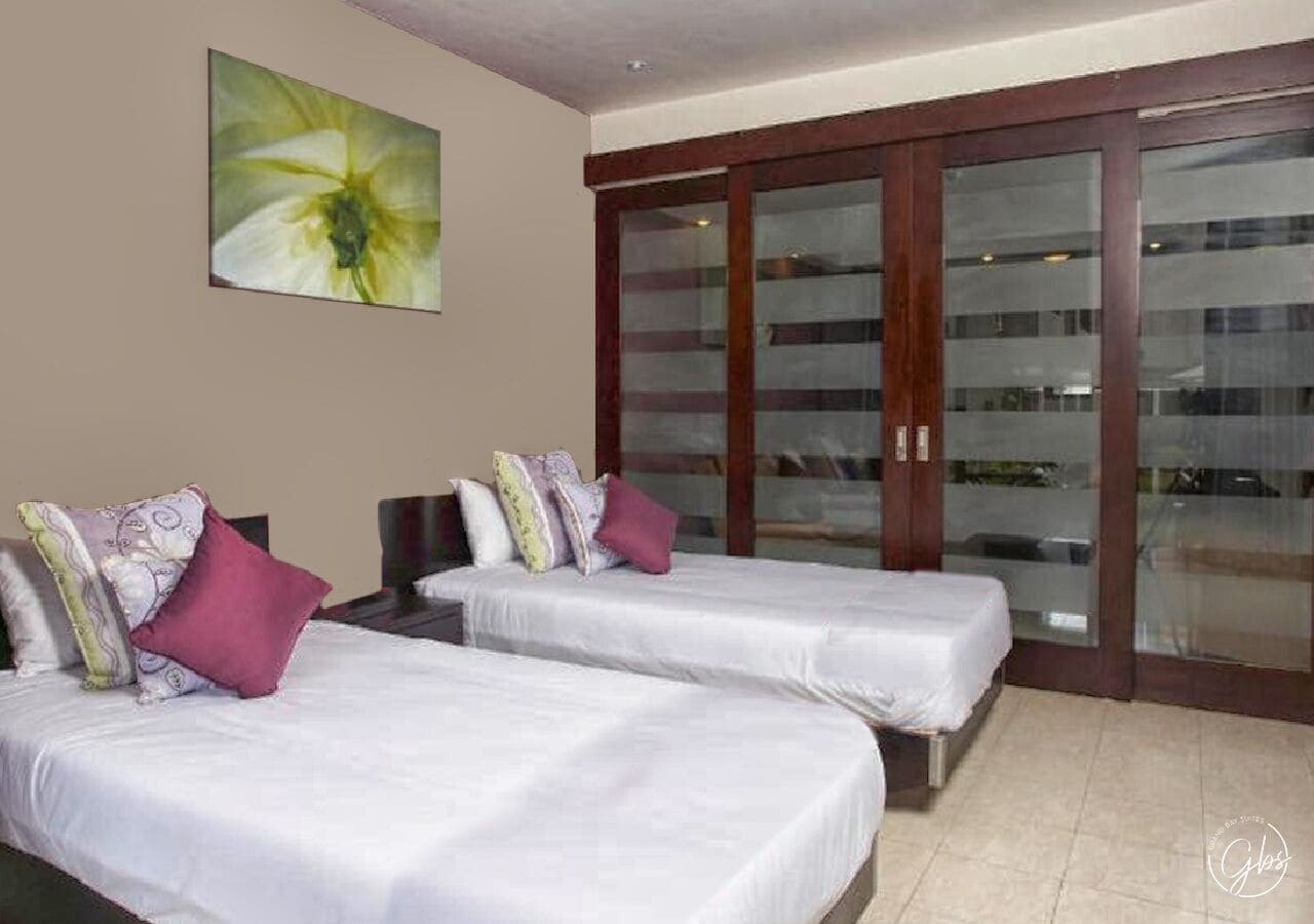 Habitación de hotel con dos camas, un ventanal grande y una puerta corredera de cristal.