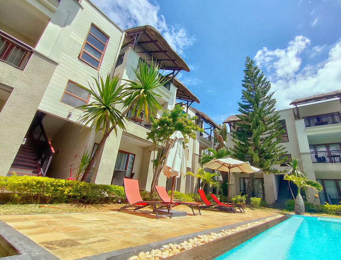 Un resort con piscina, sillas de descanso y palmeras.