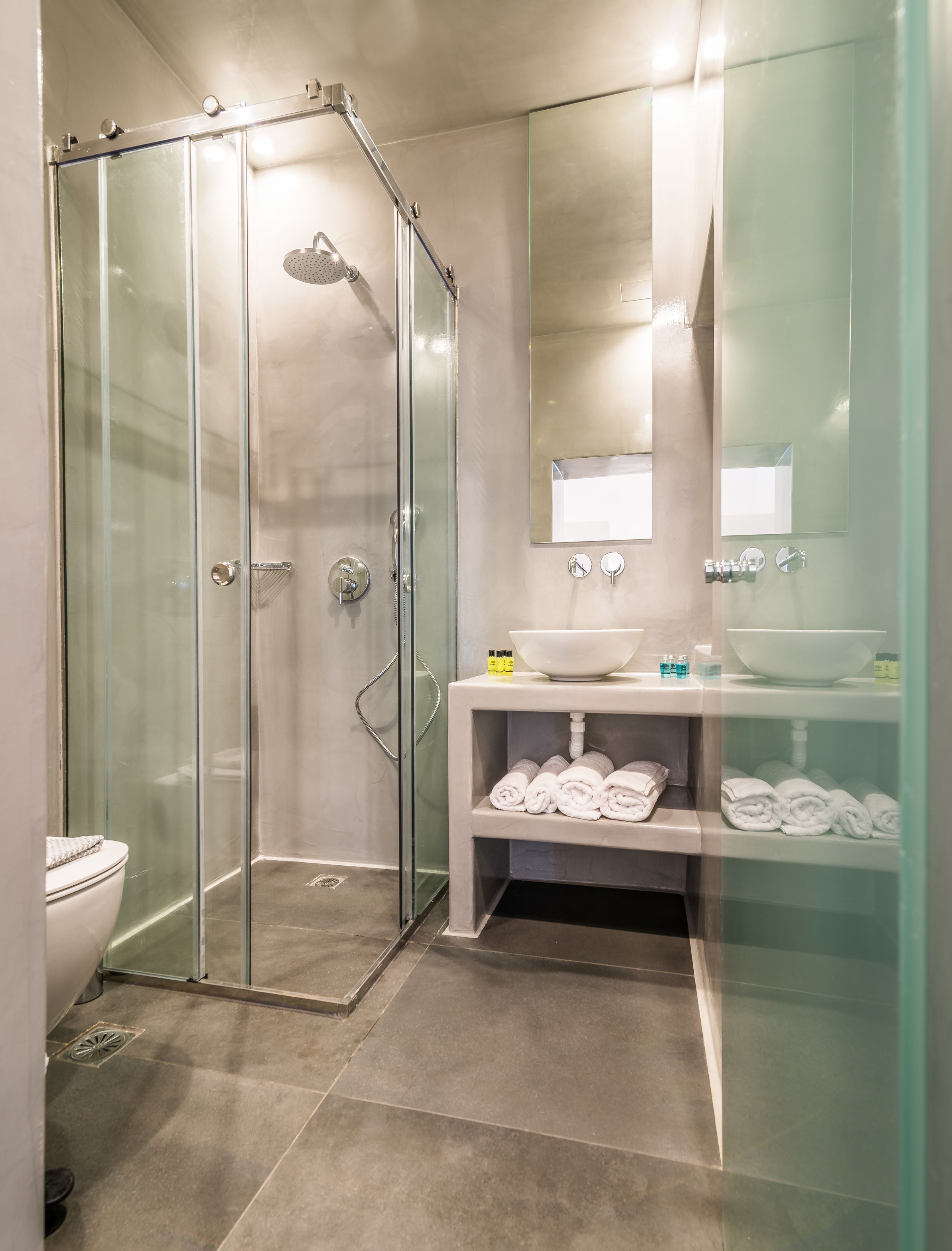 A modern bathroom with a glass-enclosed shower, a white sink, and a mirror above it.