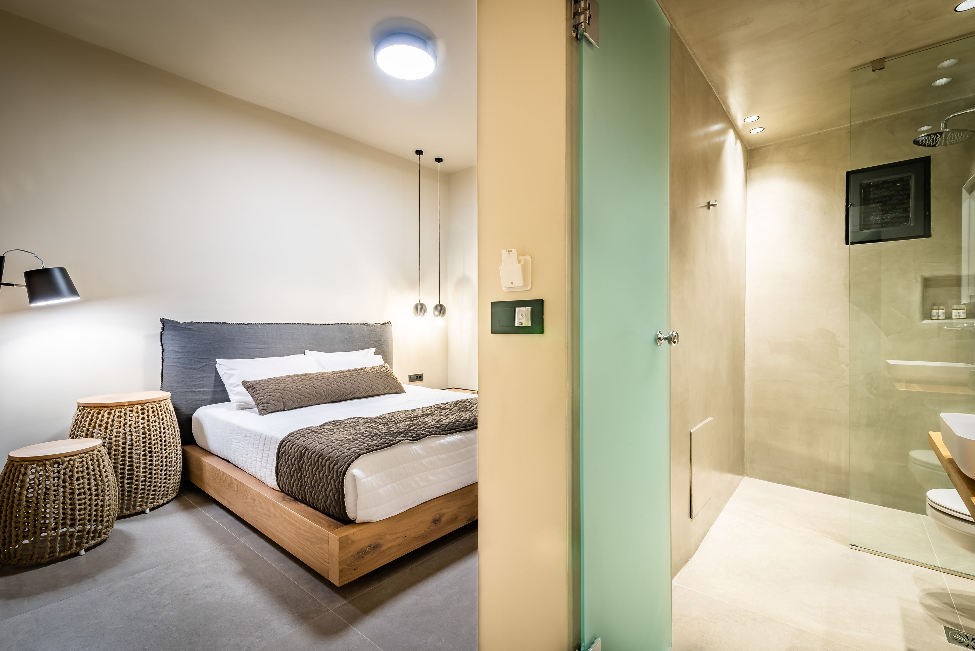 Un dormitorio con cama de madera, lámparas de noche y taburetes de mimbre.