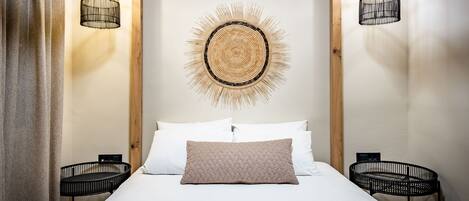 A neatly arranged bedroom with a bed, two bedside tables, and a unique wall art piece above the bed.
