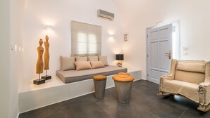 Un soggiorno moderno con un divano, due poggiapiedi, una poltrona e sculture in legno decorative.