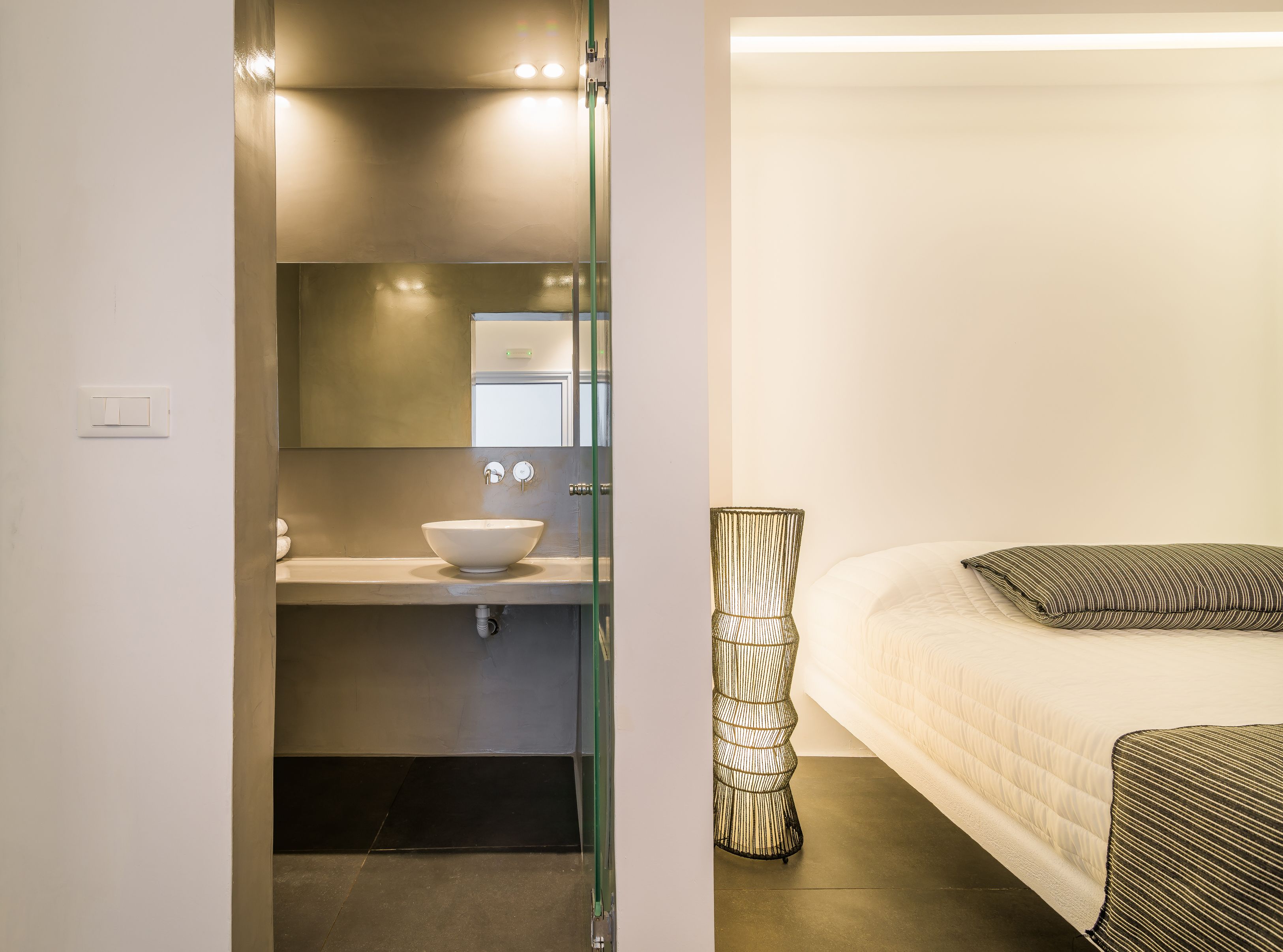 A modern bathroom with a glass partition, a white sink, and a mirror above it.
