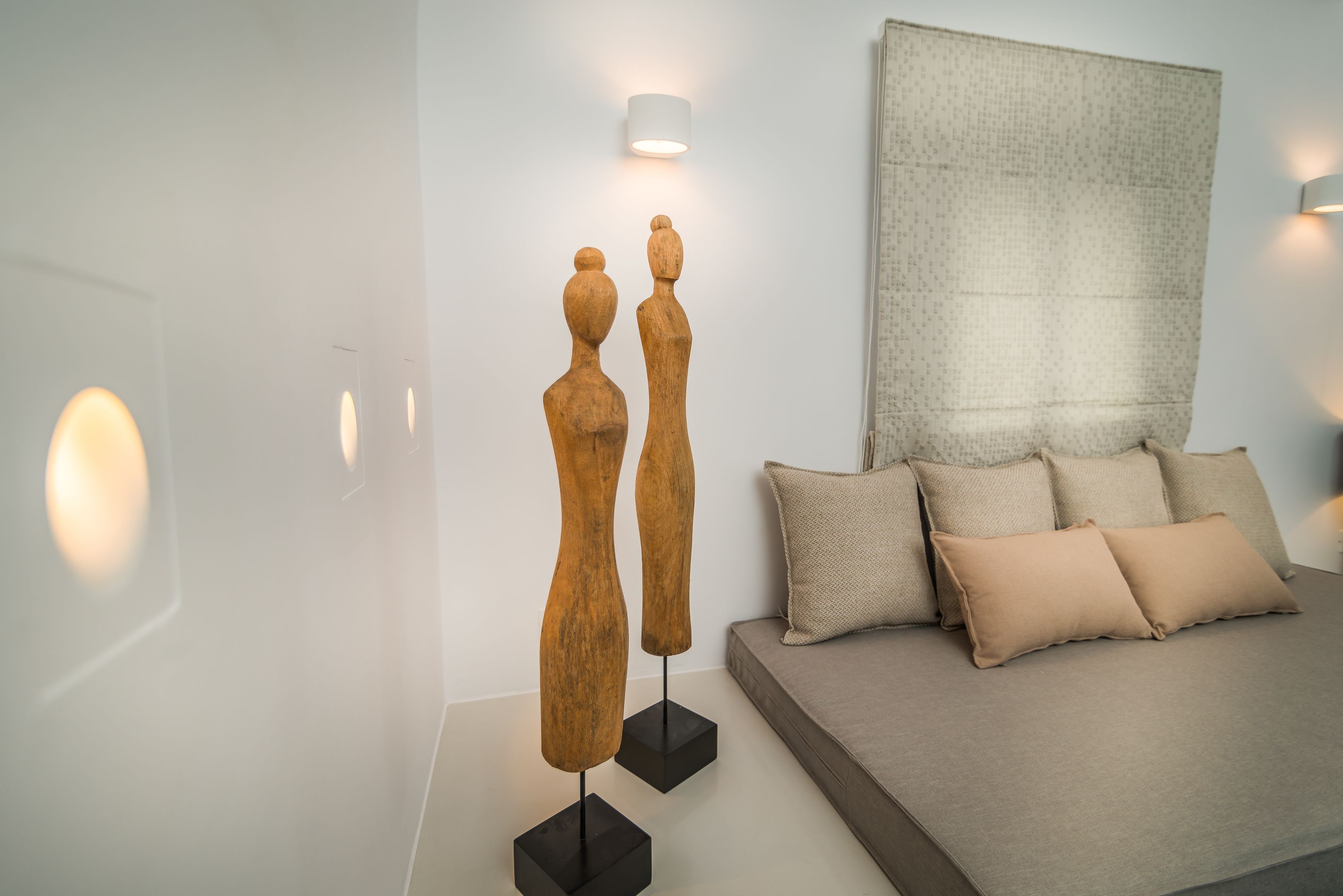 Ein modernes Schlafzimmer mit einem Bett, dekorativen Holzskulpturen und einem strukturierten Wandbehang.