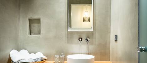 Un baño moderno con un espejo grande, un lavabo redondo y una encimera de madera.