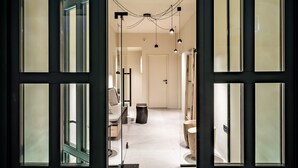 Porta aperta che mostra un interno moderno con un corridoio, un divano, un tavolino da caffè e una scultura decorativa.