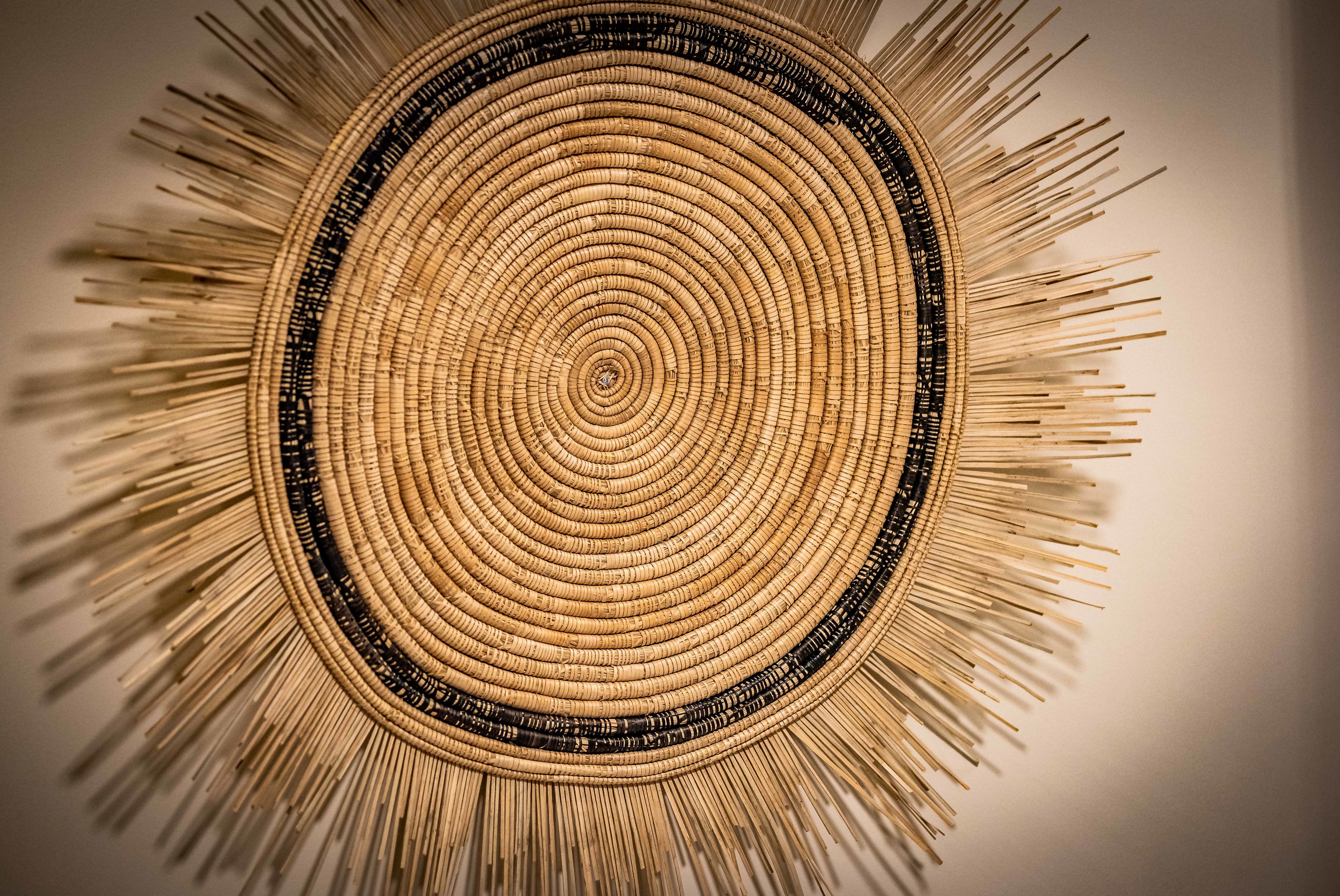 A circular woven wall hanging with concentric circles and a central point.