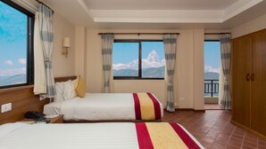 A hotel room with two beds, a view of a mountain, and a balcony with a railing. - Hotel Utsab Himalaya (Pokhara)