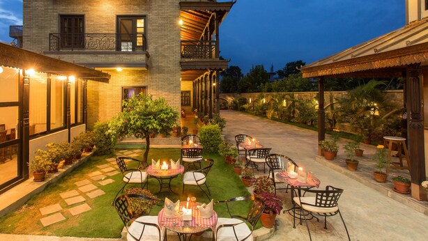A courtyard with outdoor seating, potted plants, and a building with a balcony. - Hotel Utsab Himalaya (Pokhara)