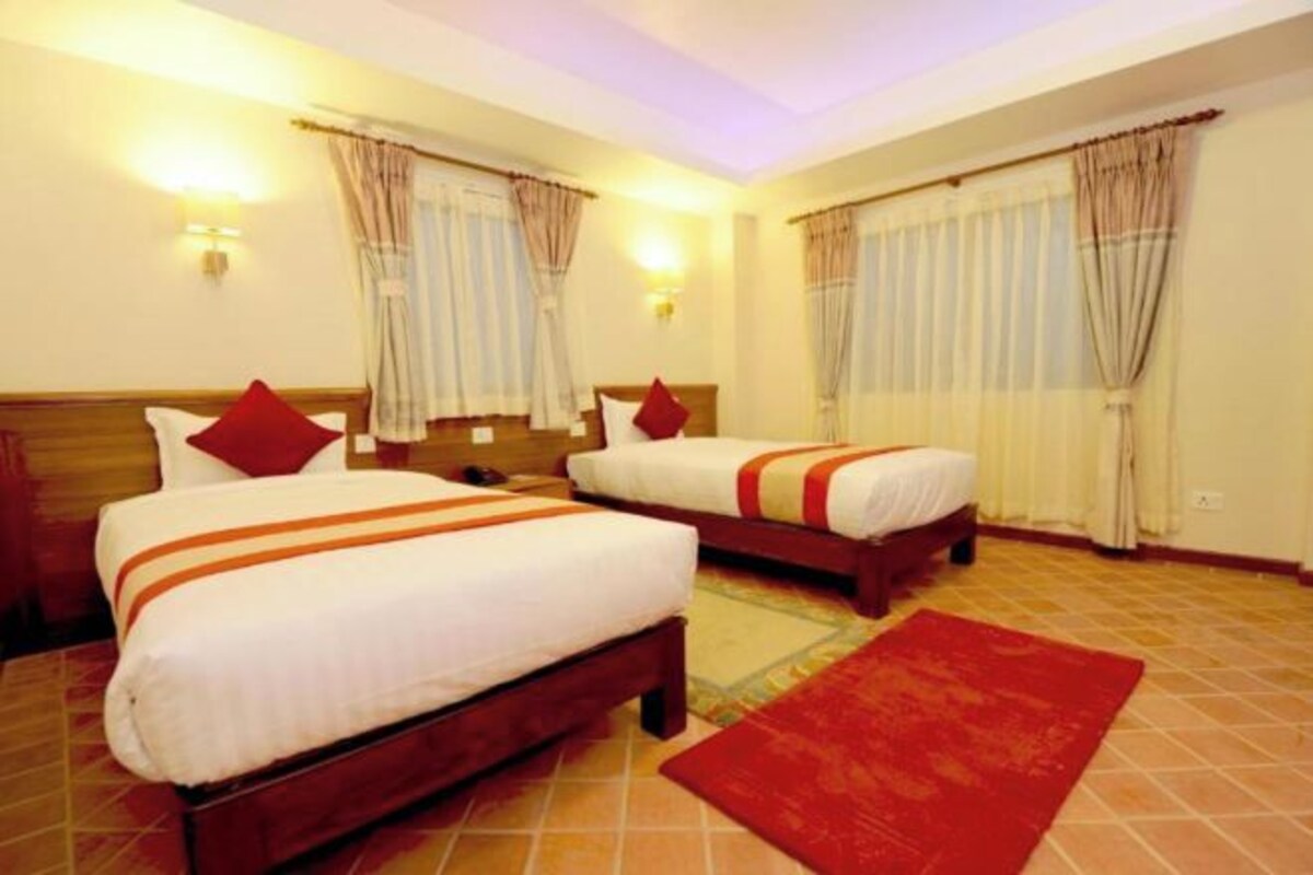 Habitación de hotel con dos camas, un tapete rojo y cortinas en las ventanas.
