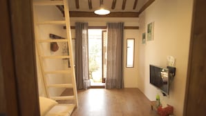 A room with a wooden floor, a bed, a TV mounted on the wall, and a window with curtains. - Ga In Dang (Jeonju)