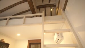 A staircase with wooden beams and white railings, an air conditioning unit, and a door with a window. - Ga In Dang (Jeonju)