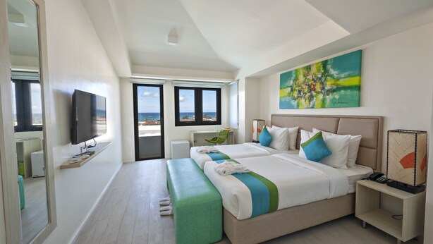 Een moderne hotelkamer met een groot bed, een televisie, een bureau en uitzicht op zee.