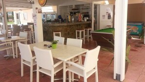 En restaurant med udendørs siddepladser, en disk og et billardbord.